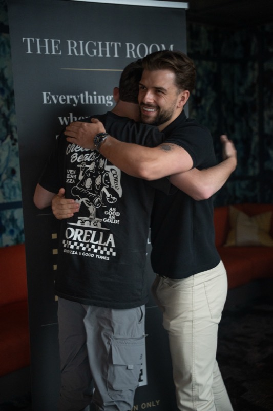 A welcome hug in front of The Right Room banner